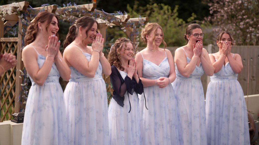 Bride revealing her dress, hair and makeup to bridesmaids