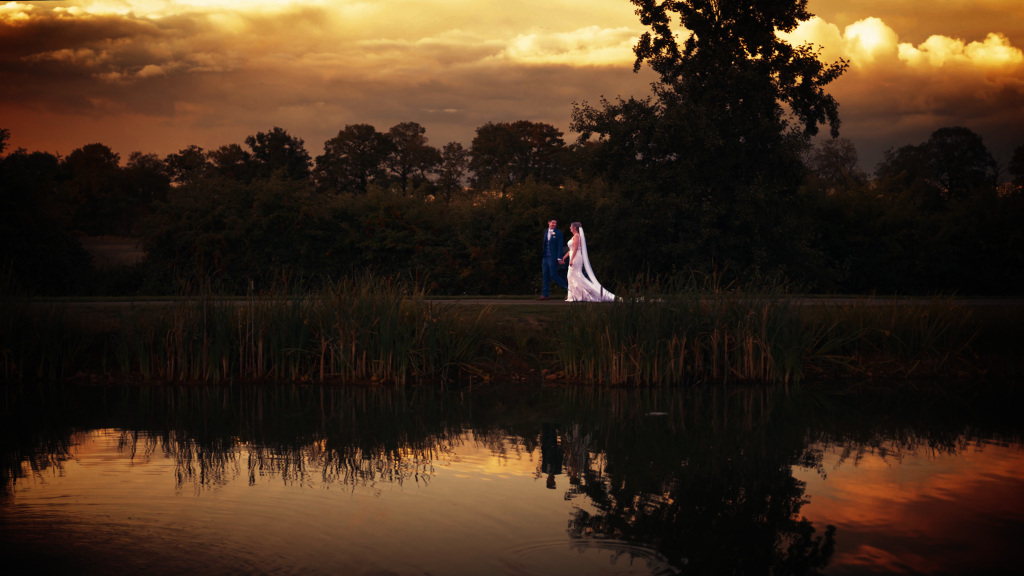 Drone capturing wedding couple walking by the lake at sunset